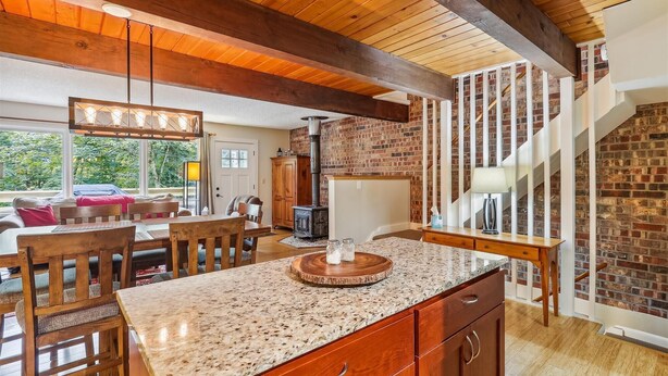 Una cocina amplia con encimera de granito, armarios de madera y pared de ladrillo.