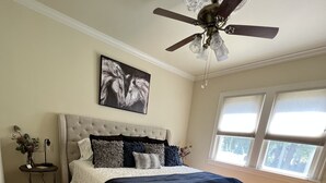 A bedroom with a large bed, a ceiling fan, a window with blinds, and a small side table with a vase. - “New” Elizabethtown Poplar Place! (Elizabethtown)