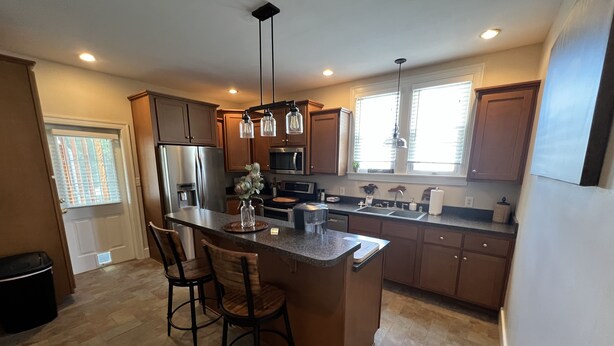 A modern kitchen with a central island, stainless steel appliances, and pendant lighting. - “New” Elizabethtown Poplar Place! (Elizabethtown)