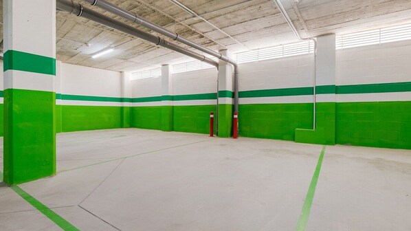 An indoor parking garage with white and green walls, concrete floors, and red bollards.
