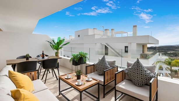 Een modern balkon buiten met een eethoek, zitplaatsen en uitzicht op de stads skyline.