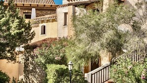 Un bâtiment doté d’une façade en pierre, d’un toit recouvert de tuiles en terre cuite et d’un escalier menant à un étage supérieur.