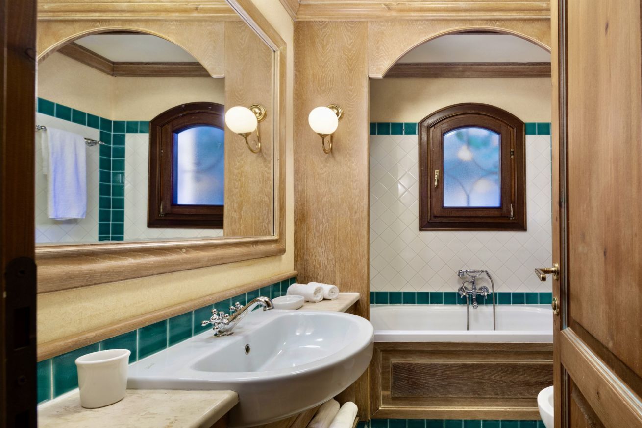 A bathroom with a large sink, a bathtub, and two wall-mounted lights.