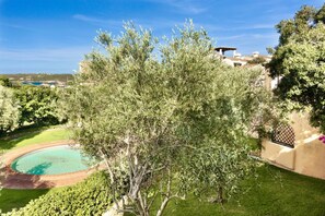 Ein Pool, umgeben von üppiger Vegetation und einem Gebäude im mediterranen Stil mit Blick auf das Meer.