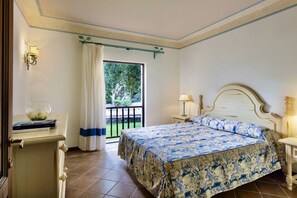 Ein Schlafzimmer mit Bett, Nachttisch, Lampe, Kommode und einem Fenster mit Vorhängen.