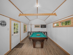 A pool table in a room with wooden beams, a door, and a sign on the wall. - Luxury Cabin 45 Min to Asheville |Hot Tub|Fire pit (Marion)