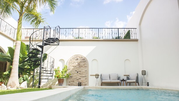 A pool area with a spiral staircase, stone wall, and seating by the pool. - Casa Ixchel | A Modern Mexican Oasis | Private Pool (San Miguel de Cozumel)