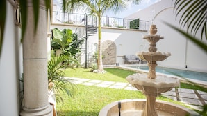 A courtyard with a fountain, a pool, and a staircase leading to a balcony. - Casa Ixchel | A Modern Mexican Oasis | Private Pool (San Miguel de Cozumel)