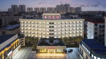 A multi-story hotel with a prominent sign, a courtyard with a seating area, and a view of the surrounding cityscape.