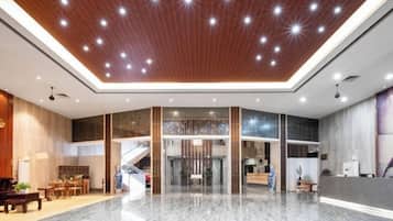 A spacious lobby with a high ceiling, a reception desk, and a staircase leading to an upper level.