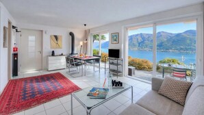 Een ruime woonkamer met een eettafel, bank en een groot raam met uitzicht op de bergen.