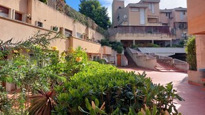Un pati interior amb una escala que condueix a plantes superiors, envoltat de vegetació i edificis amb balcons.