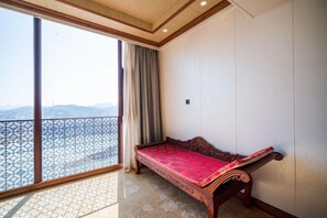 A balcony with a wooden bench, a patterned floor, and a view of mountains. - Gujiang Hotel (Dahua)