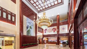 Un hall d’entrée spacieux avec un plafond haut, un grand lustre et un comptoir d’accueil.
