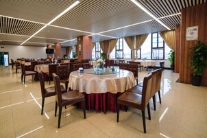Un comedor amplio con mesas redondas, sillas y una pieza decorativa central.