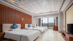 Une chambre d’hôtel avec trois lits, une télévision et un balcon avec vue.