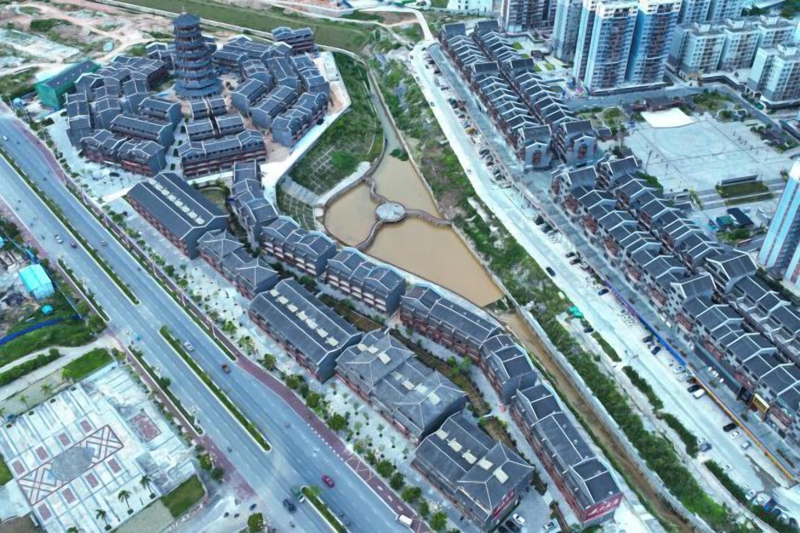 Ett flygbildsbild av ett bostadsområde med en central rondell, omgivet av högre byggnader, och korsande vägar.