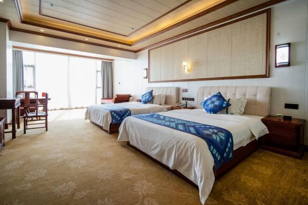 Ett hotellrum med två sängar, ett skrivbord och en stol.