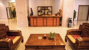 Un vestíbulo con mostrador de recepción, muebles de madera y una planta.