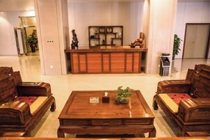 Un vestíbulo con mostrador de recepción, muebles de madera y una planta.
