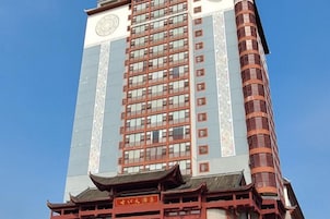 Un edificio alto con una torre de reloj y una sección arquitectónica tradicional en la parte inferior.