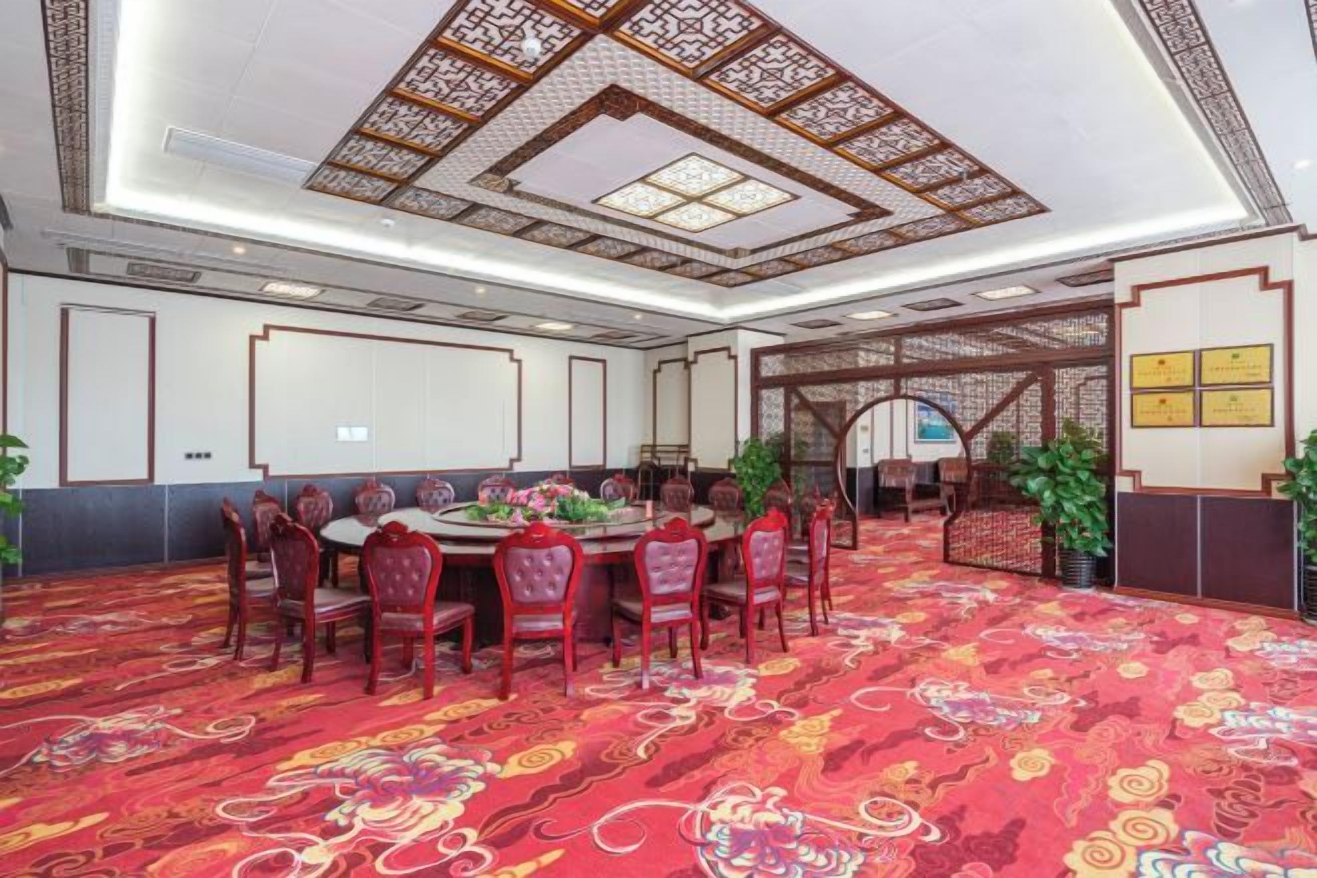 Ein Konferenzraum mit rundem Tisch, Stühlen, einem gemusterten Teppich und traditioneller Deckenkonstruktion.
