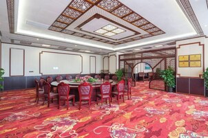 A conference room with a round table, chairs, a patterned carpet, and a traditional ceiling design.