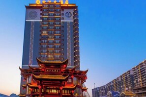 A high-rise building with traditional architectural elements at the base, modern upper floors, and a clear sky in the background. - Gujiang Hotel (Dahua)