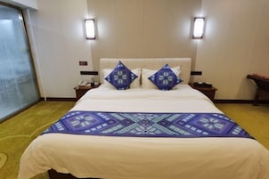 Una habitación de hotel con una cama grande, dos mesitas de noche con lámparas y un ventanal con vistas.