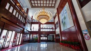 A spacious lobby with a chandelier, large windows, and a red carpet.