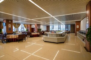 Un amplio espacio interior con mesas y sillas dispuestas para comer, una barra central y un diseño moderno del techo.