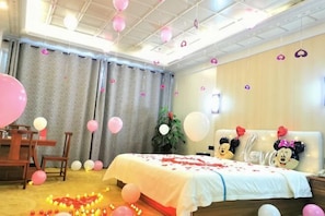 A room with a bed, a desk, and a chair. There are balloons and a plant. - Gujiang Hotel (Dahua)