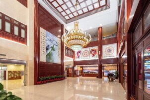 A spacious lobby with a high ceiling, a chandelier, and a large mural.