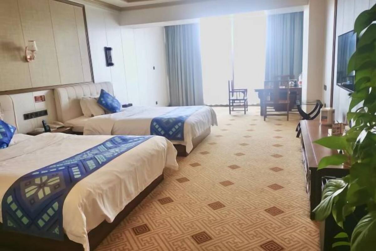 Ett hotellrum med två sängar, ett skrivbord och en stol.