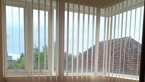 A room with a large window, a bed with a striped bedspread, and a pink blanket. - PAPADAAN Homestay Syariah Batu (Batu)