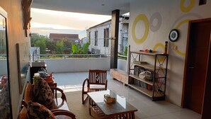 A modern living room with a glass table, wooden chairs, a sofa, and a bookshelf. - PAPADAAN Homestay Syariah Batu (Batu)