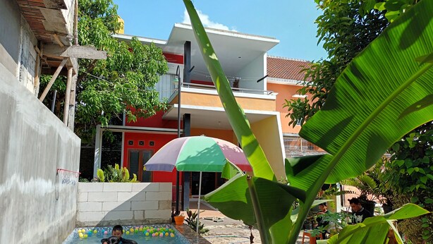 A swimming pool area with inflatable rings, colorful balls, and a large umbrella. - PAPADAAN Homestay Syariah Batu (Batu)