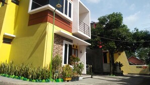 A modern two-story house with a balcony, a small porch area with potted plants, and a visible "HOME STAY" sign. - PAPADAAN Homestay Syariah Batu (Batu)
