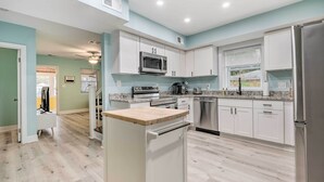 A modern kitchen with white cabinets, stainless steel appliances, and a wooden countertop. - Updated North Beach Cottage: Pet Friendly! (North Beach)