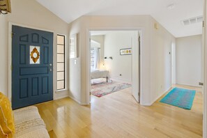 Una habitación amplia con un gran ventanal, una puerta con panel de vidrio decorativo y suelo de madera.