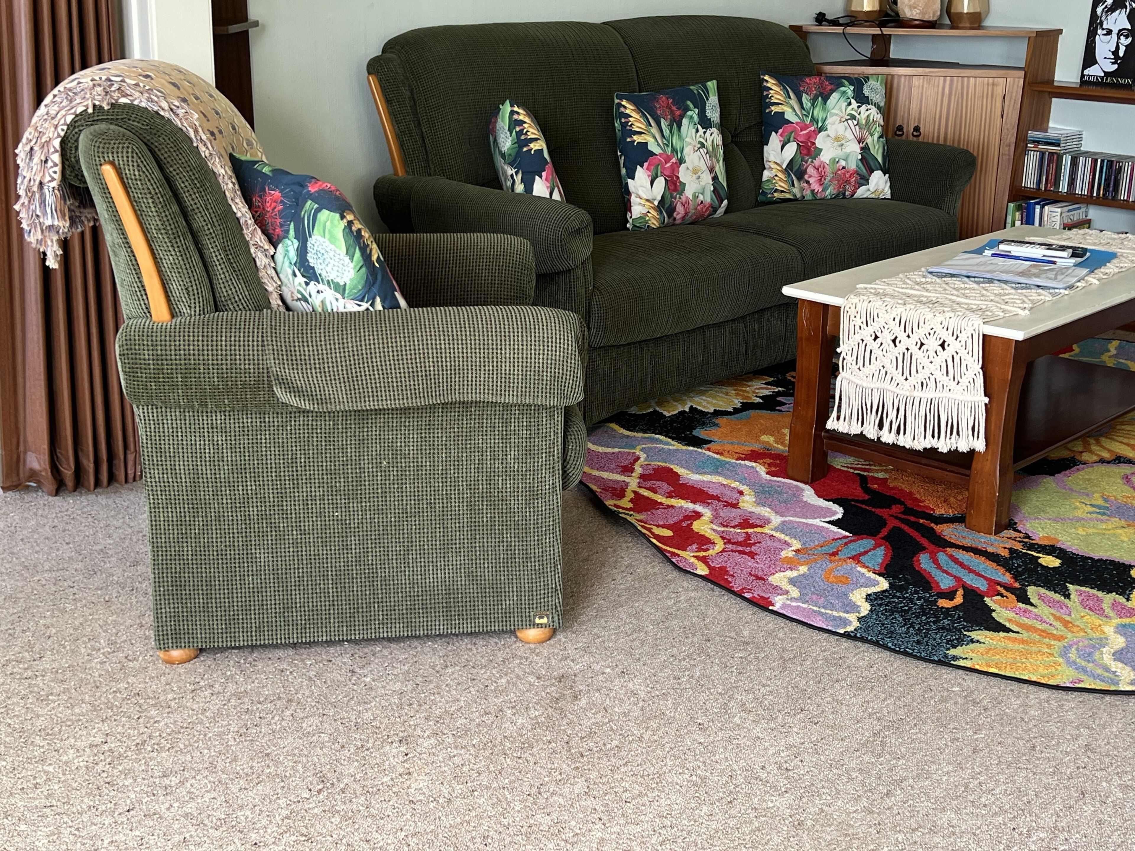 Ein Wohnzimmer mit einem grünen Sessel, einer Couch und einem Couchtisch.