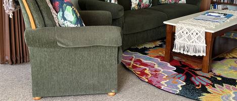 Ein Wohnzimmer mit einem grünen Sessel, einer Couch und einem Couchtisch.