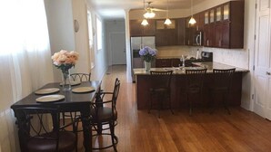 A spacious kitchen with wooden flooring, dark cabinetry, and pendant lighting.