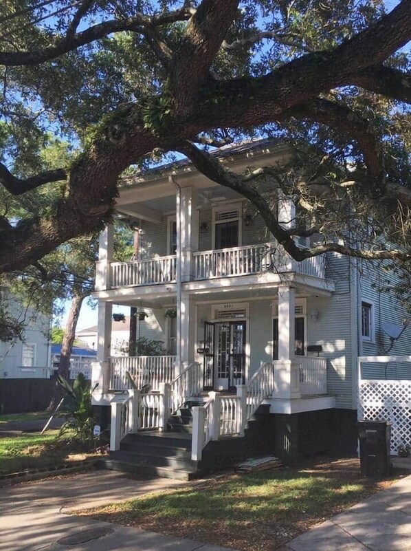 A two-story house with a porch, a front door, and a mailbox.