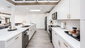 A modern kitchen with white cabinetry, stainless steel appliances, and a skylight above the island.