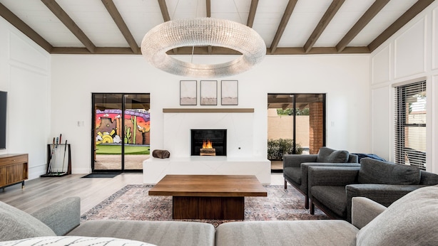 A modern living room with a fireplace, a large sofa, a coffee table, and a hanging light fixture.