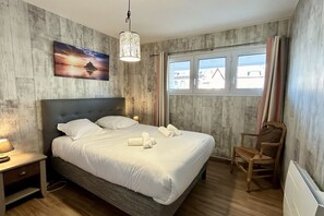 A bedroom with a bed, bedside table, chair, window, and a painting on the wall. - Appt Avec vue Exceptionnelle sur la Baie + Garage (Le Crotoy)