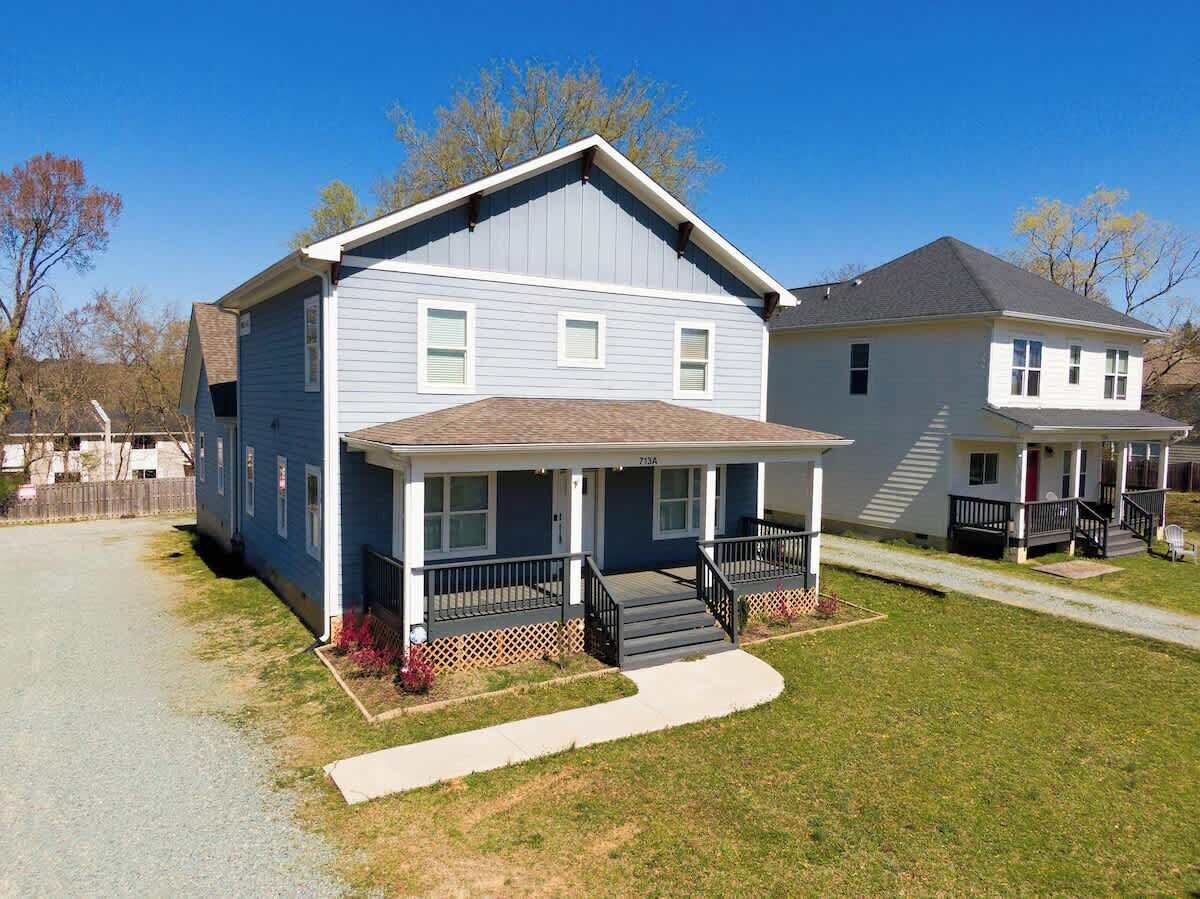 A two-story residential house with a front porch, a driveway, and a well-maintained lawn.