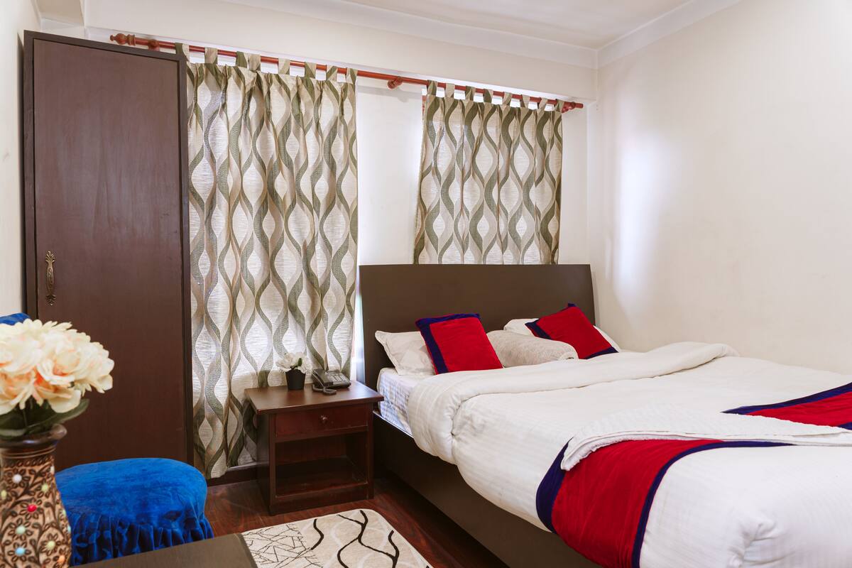 A bedroom with a bed, nightstand, dresser, and curtains.