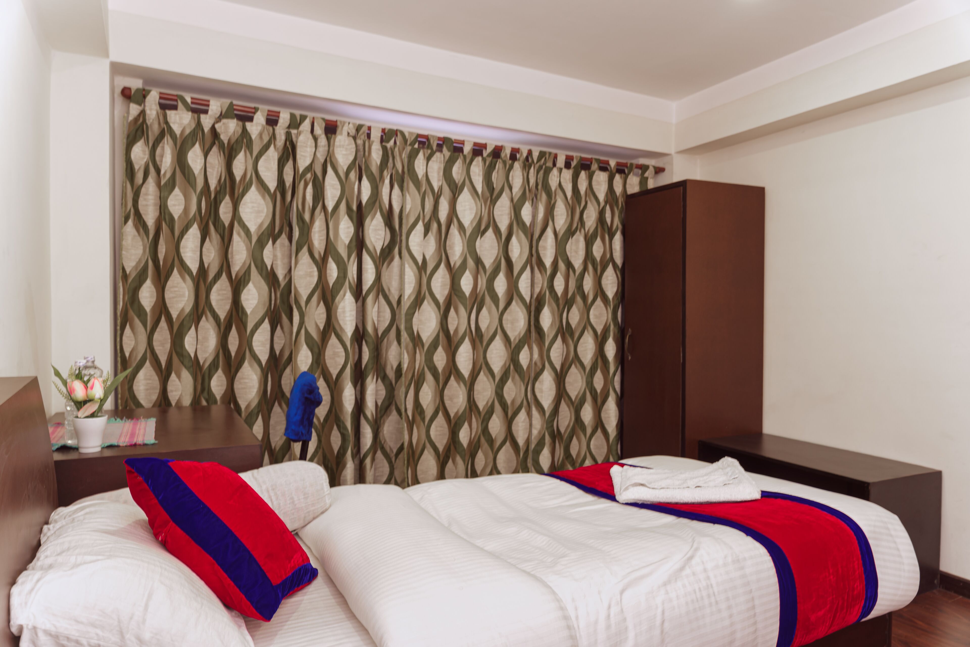 A hotel room with a bed, a nightstand, and a wardrobe.